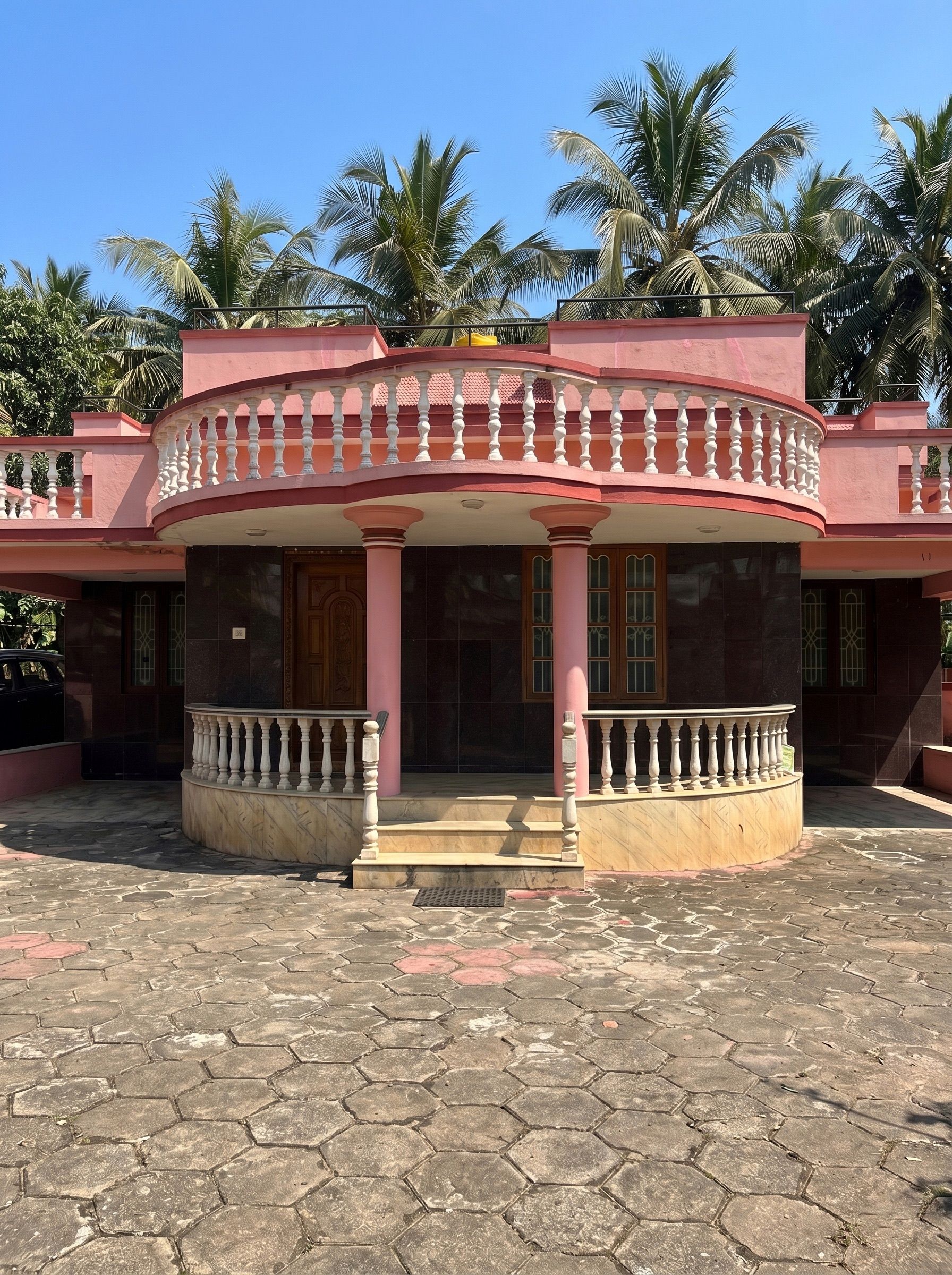 The front of the house near Panambur beach, a covered veranda and palms behind it